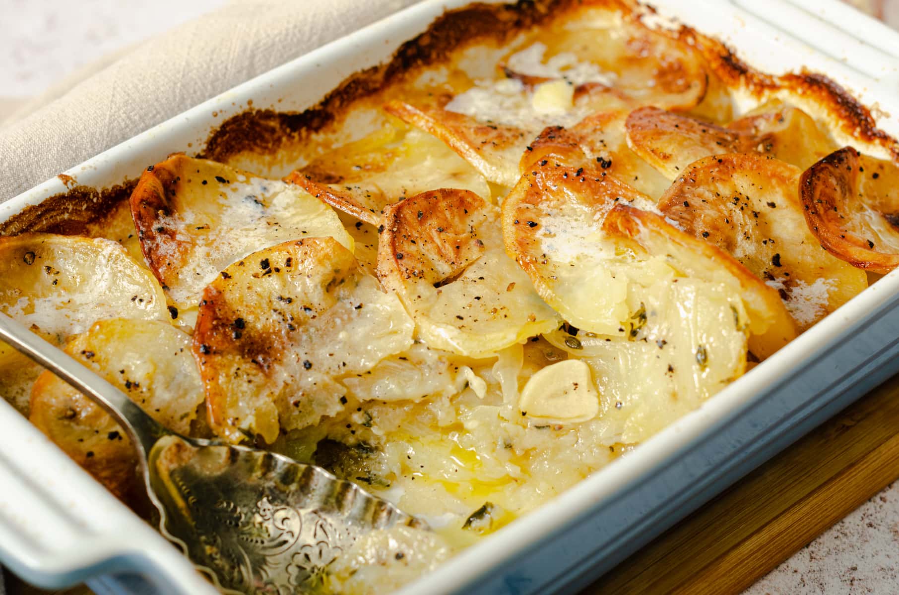 Layered boulangere potatoes with fresh thyme and lots of garlic in a family sized serving dish.