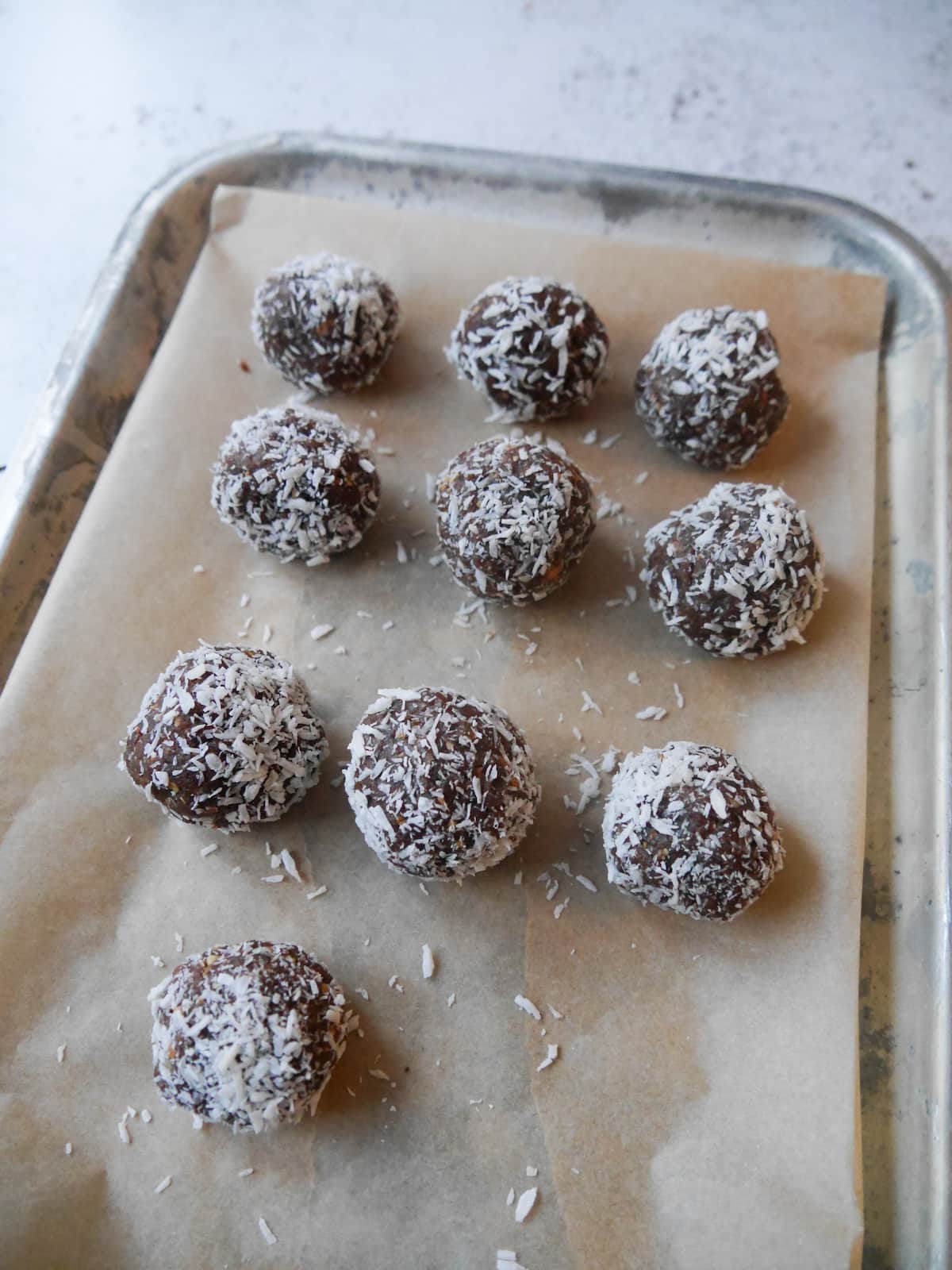 A baking tray lined with baking paper and topped with energy balls.